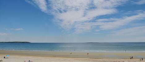 A beach with people, umbrellas, and a clear sky.