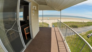 A balcony with a view of the beach, a door leading to a room, and a railing. - Friendship Oceanfront Suites (Old Orchard Beach)