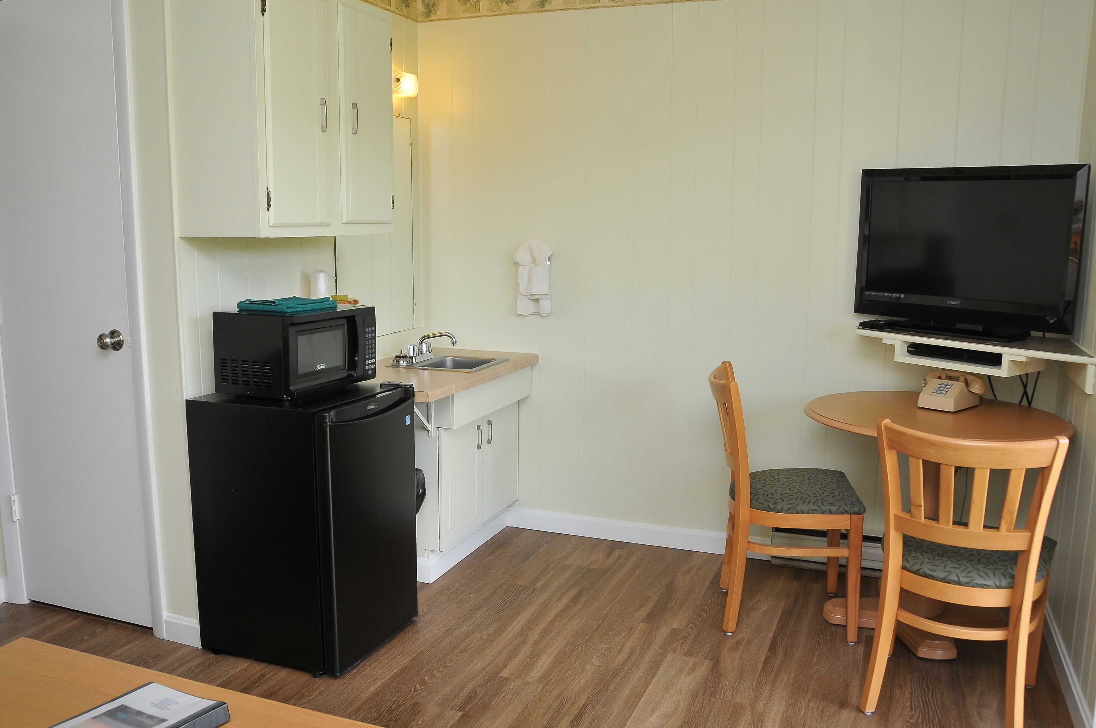 Una cocina compacta con refrigerador, microondas, pileta y una pequeña mesa de comedor con sillas.