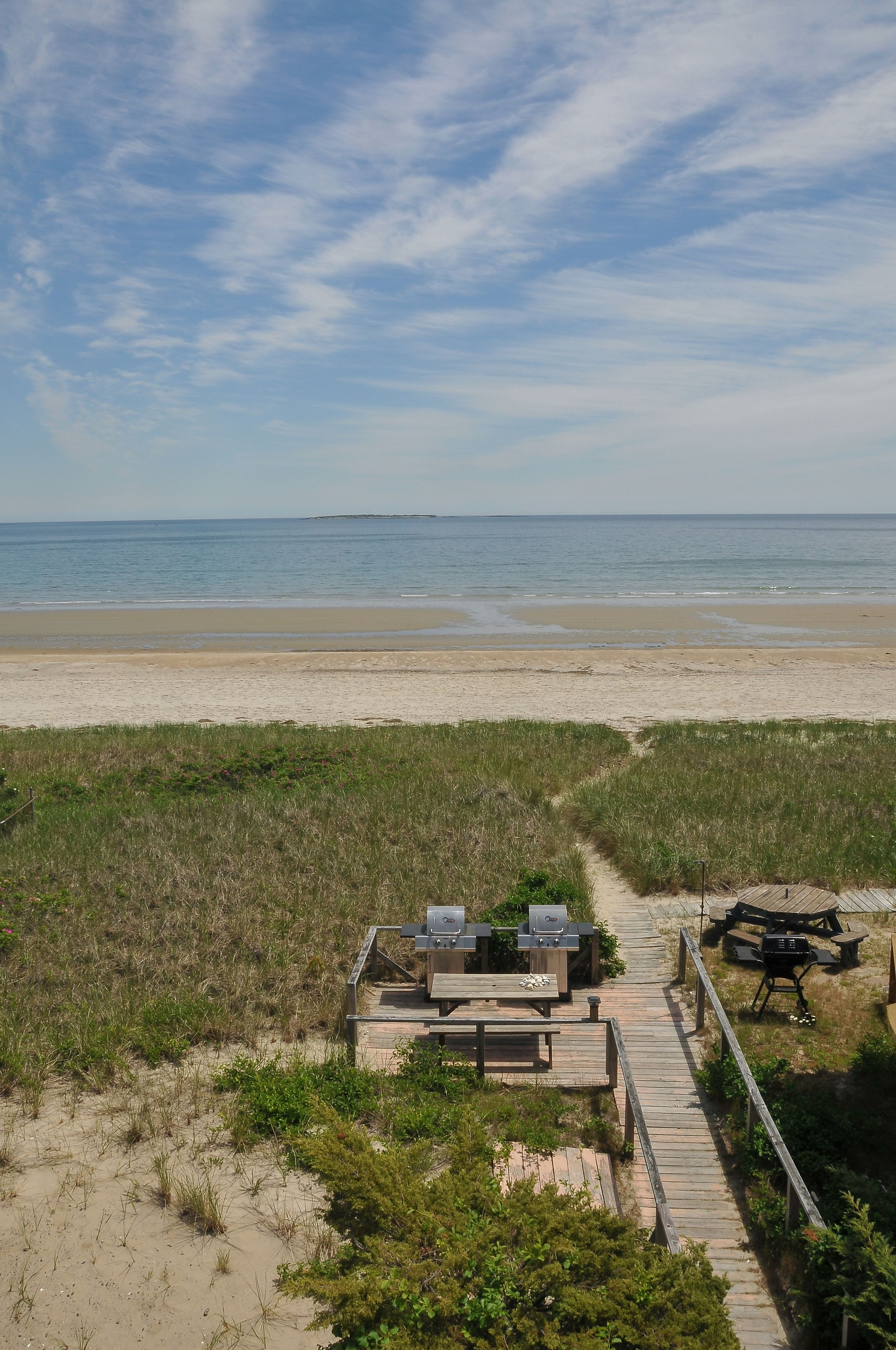 Une terrasse au bord de la plage, dotée de meubles d’extérieur et d’un barbecue, avec vue sur l’océan.