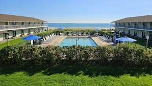 A hotel with a pool, lounge chairs, and umbrellas, overlooking the ocean. - Friendship Oceanfront Suites (Old Orchard Beach)