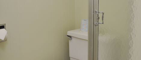 Ein Badezimmer mit Toilette, Duschkabine aus Glas und Handtuchhalter.
