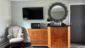 A hotel room with a flat-screen TV, a microwave, a coffee maker, a telephone, a mirror, and a wooden dresser. - Colonial Valley Motel (Farmington)