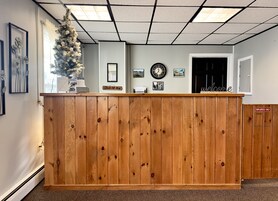 Una recepción con detalles de madera, un reloj, cuadros enmarcados y un cartel de 'Welcome'.