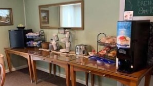 A room with a long table, a chalkboard with a welcome sign, and various food items.