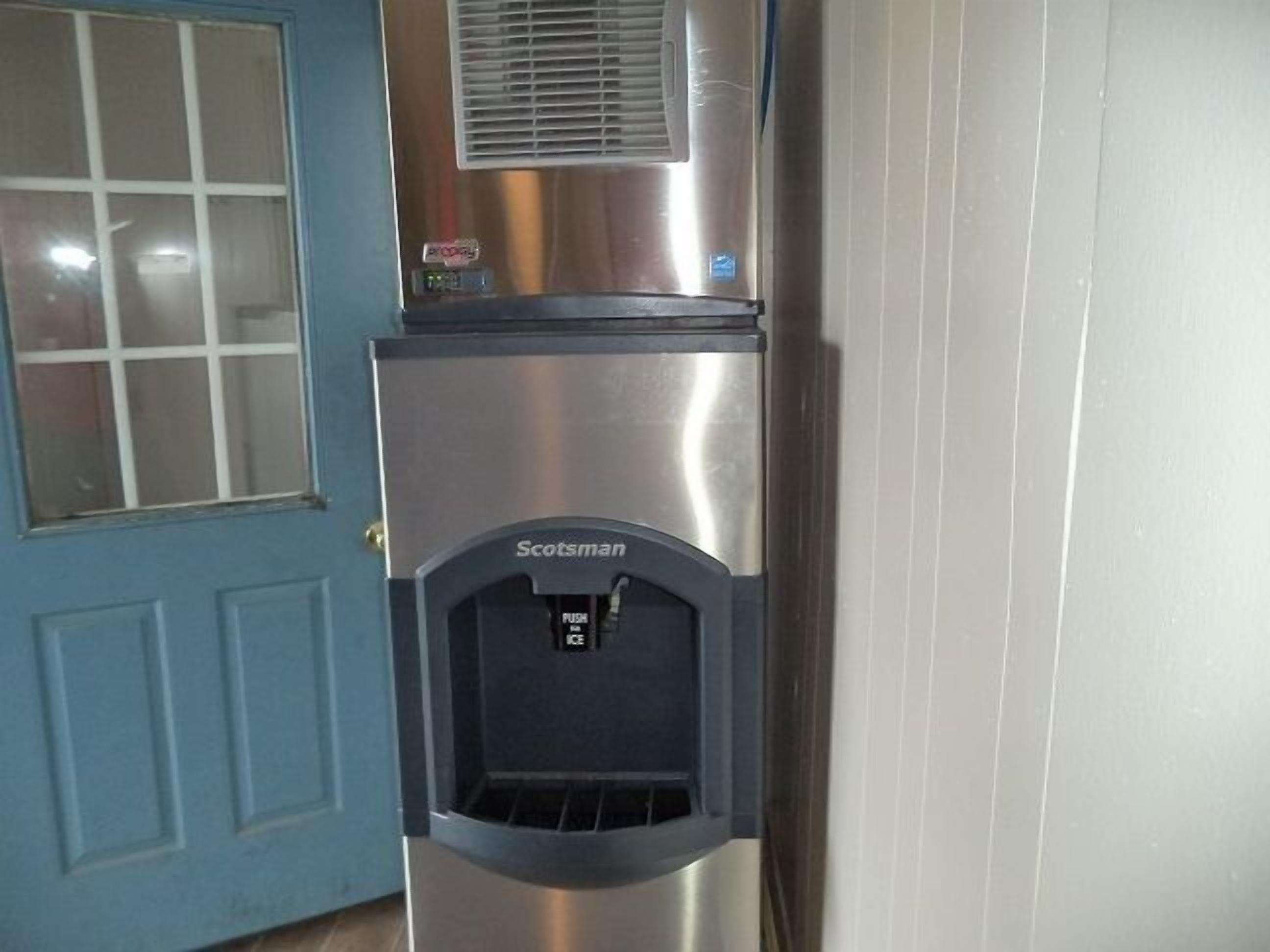 A stainless steel refrigerator with a water dispenser labeled "Scotsman" in a kitchen setting.