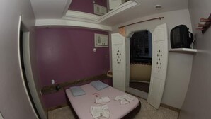 Een slaapkamer met een bed, een televisie en een kledingkast.