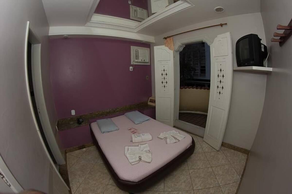 A bedroom with a bed, a television, and a wardrobe.