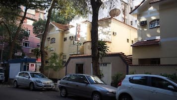 Un hotel llamado "HOTEL LIDO" con un letrero, coches aparcados y edificios circundantes.