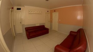 Een kamer met een rode bank, witte wanden en een betegelde vloer.
