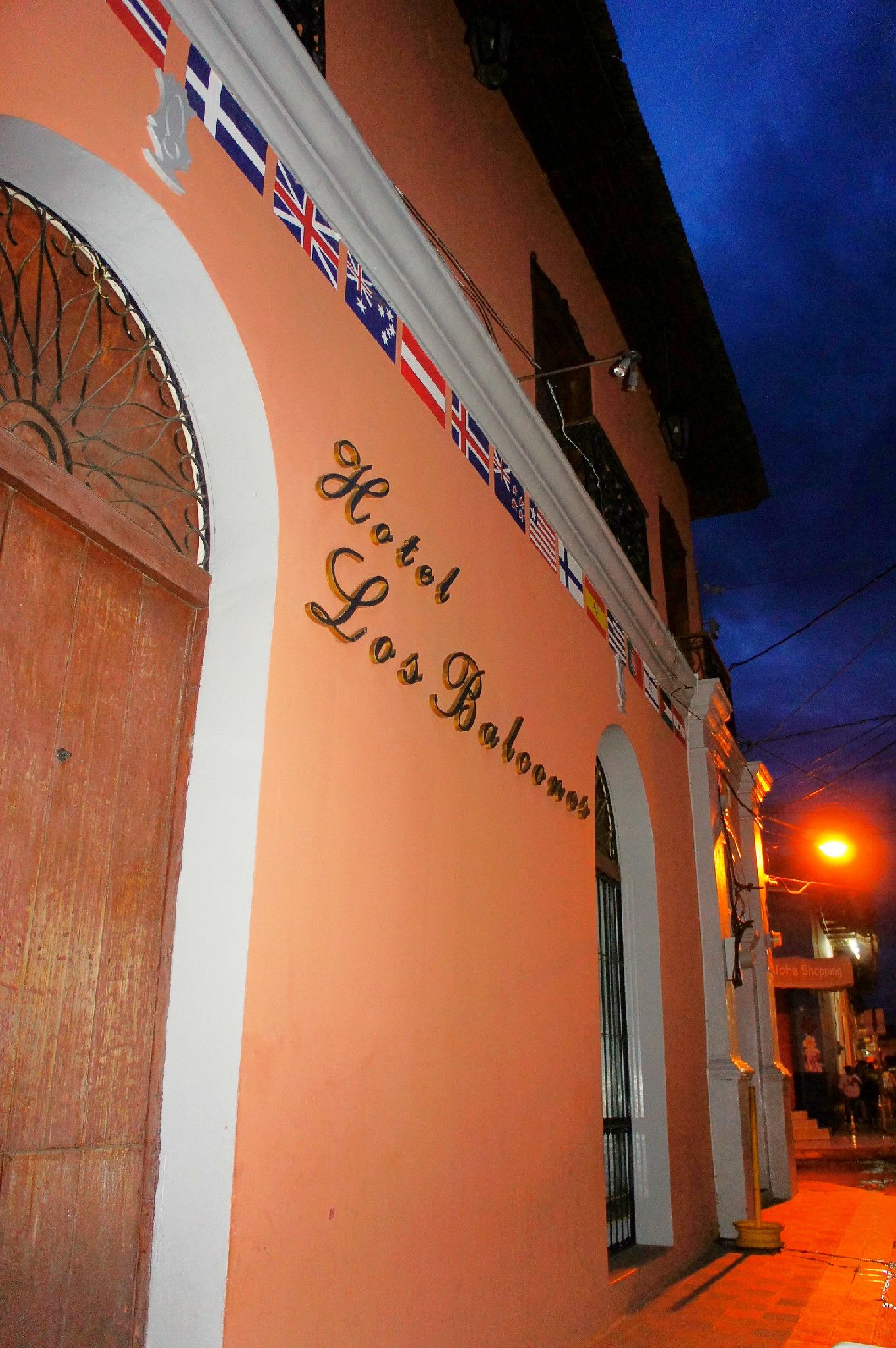 A hotel facade with the name "Hotel Los Balones" and multiple flags.