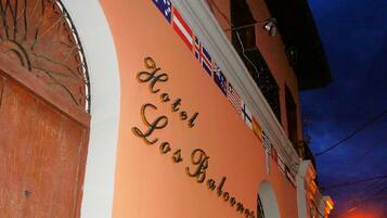 A hotel facade with the name "Hotel Los Balones" and multiple flags.