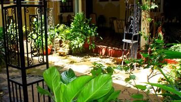 En innergård med en pergola, krukväxter och utemöbler.