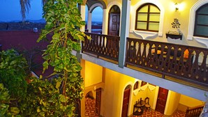 Ein zweistöckiges Gebäude mit einem Balkon, Bogenfenstern und einem roten Teppich vor dem Eingang.