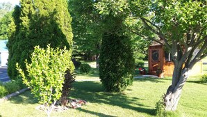 A well-maintained garden with various trees and a wooden structure.