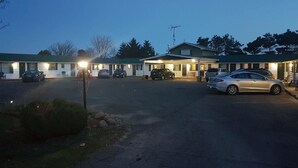 A motel with multiple rooms, a covered parking area, and a small outdoor seating area.
