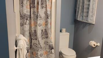 A bathroom with a shower curtain featuring architectural designs, a toilet, and a sink.