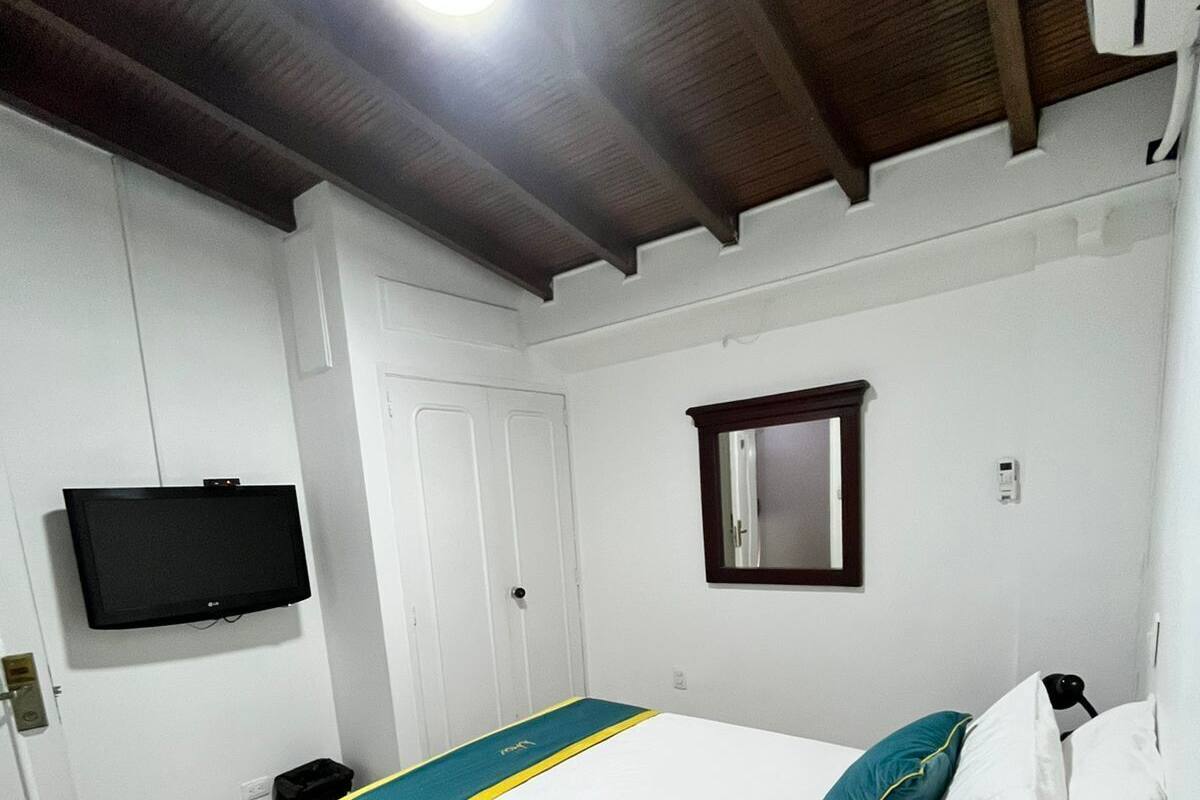 A bedroom with a bed, a television, a door, and a window.