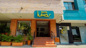 En hotelindgang med et skilt, der viser "Hotel Lukas", og en tydelig trappe, der fører op til indgangen.