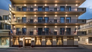 Ein Hotel mit mehreren Balkonen, Flaggen und einer gut beleuchteten Fassade.