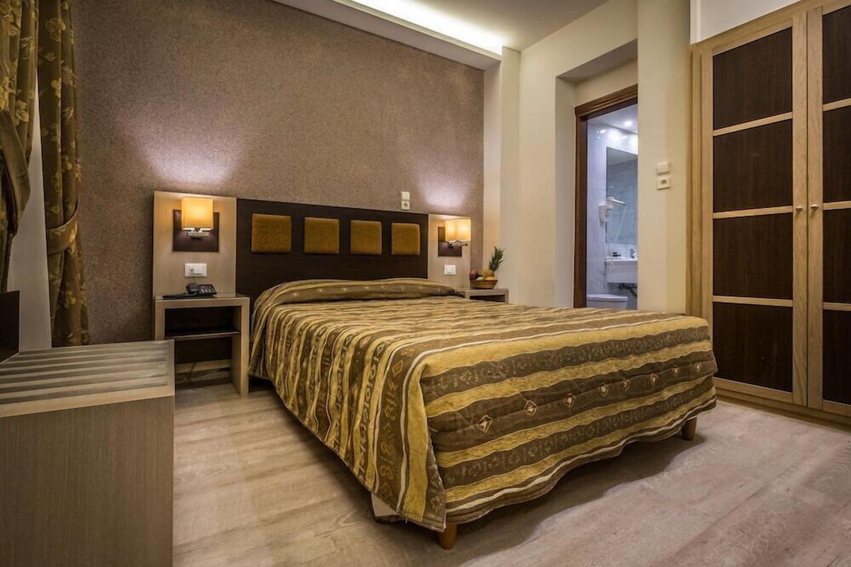 A bedroom with a large bed, bedside tables, a wardrobe, and a bathroom visible through an open door.