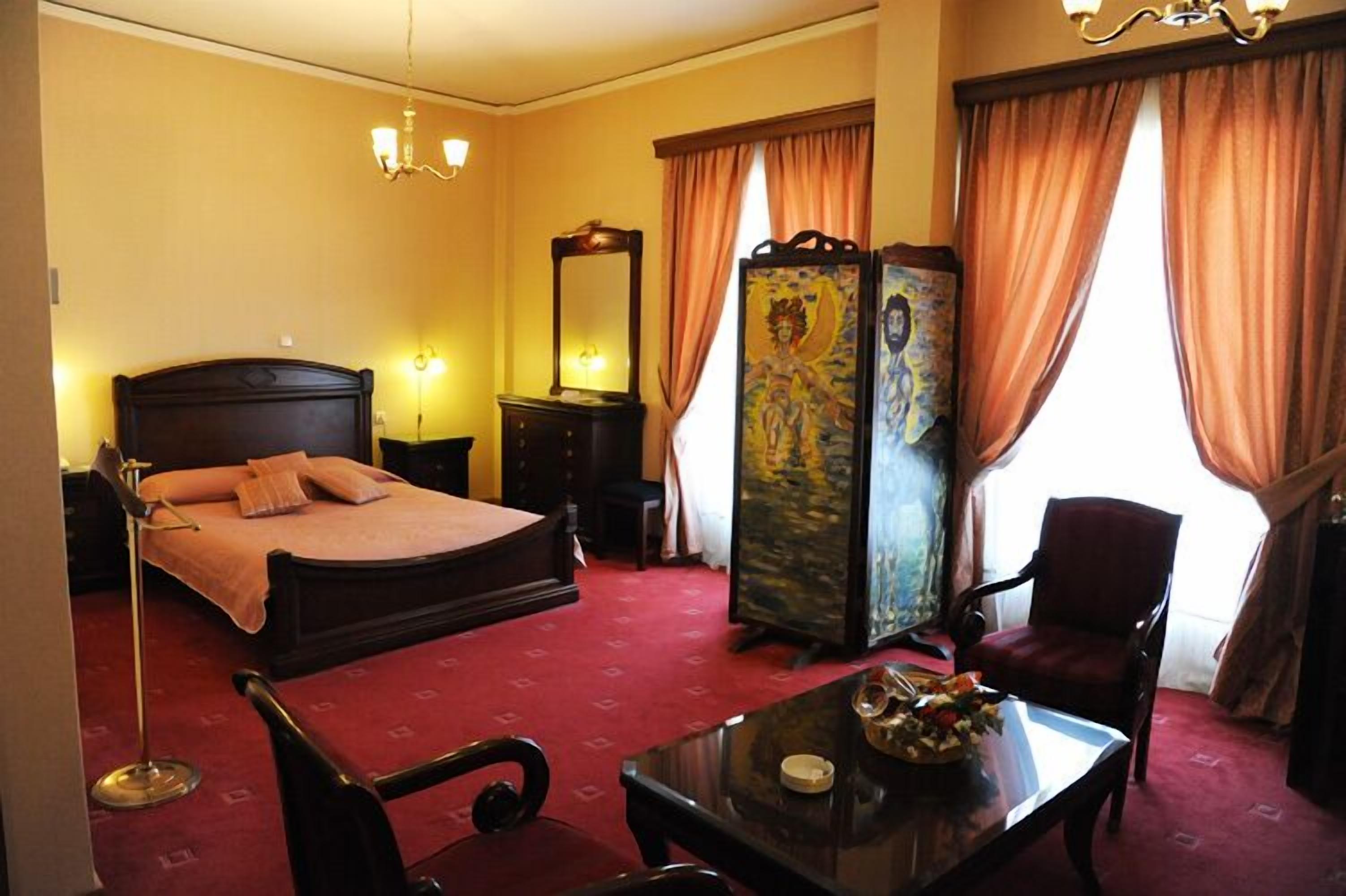A hotel room with a bed, a desk, a chair, a wardrobe, and a mirror.
