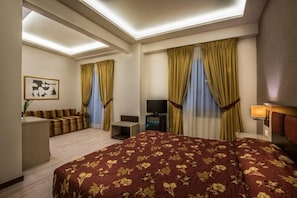 Une chambre d’hôtel avec un grand lit, un canapé, un bureau, une télévision et des rideaux.
