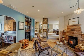 Un salon chaleureux avec une cheminée, des étagères à livres et des fauteuils confortables.