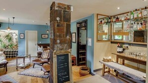 A cozy bar area with a stone pillar, wooden furniture, and a wall of liquor bottles. - Hightae B&B (Lockerbie)