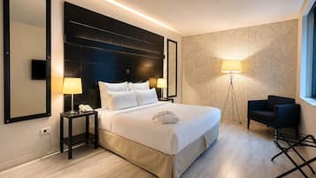 Habitación de hotel con una cama grande, lámparas de noche, un escritorio, una silla y una pared con diseño.