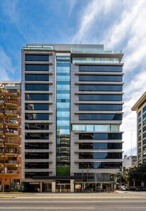 Un bâtiment moderne à plusieurs étages, doté d’une façade en verre, d’un toit plat et d’une entrée au niveau du sol.