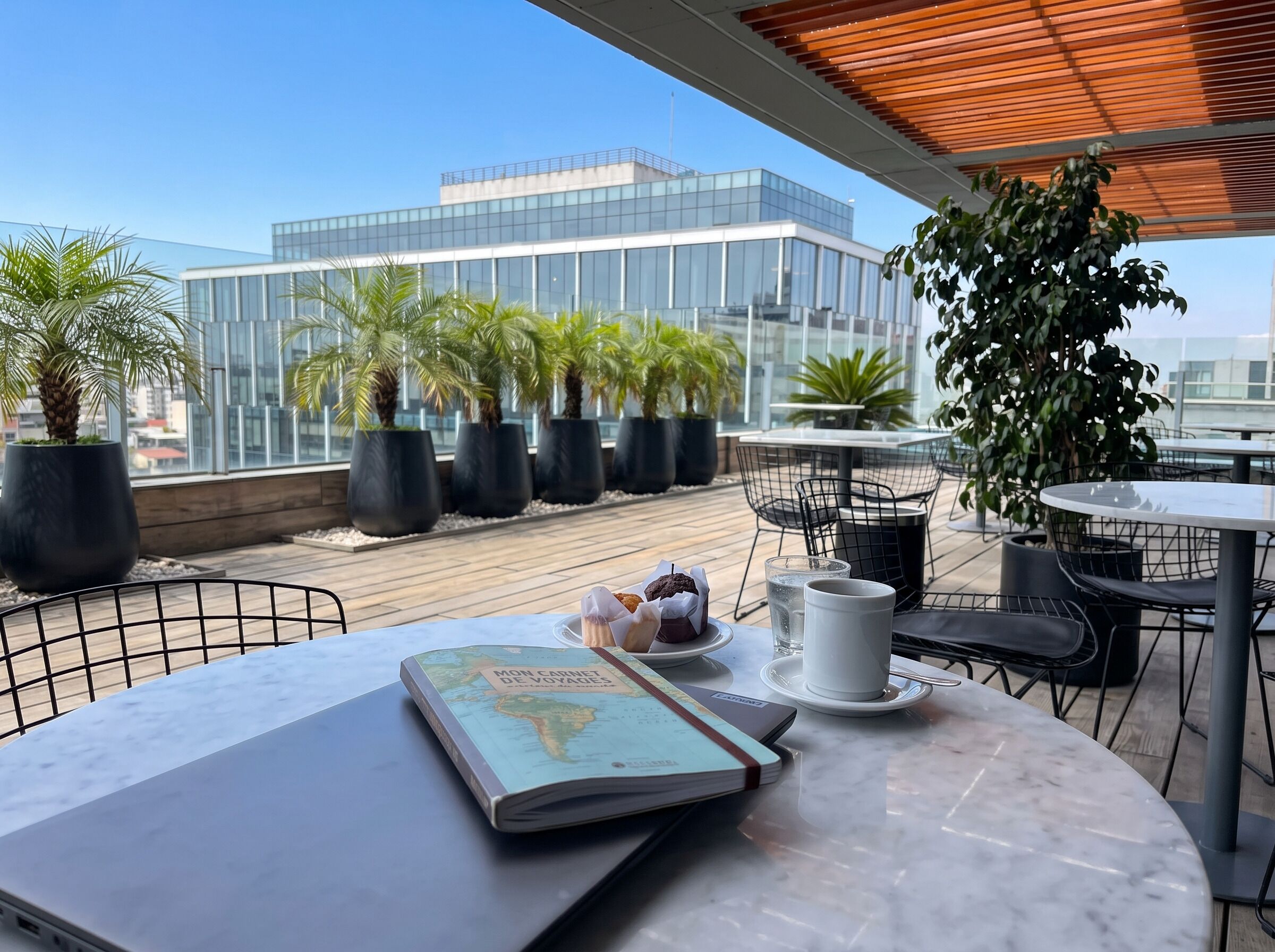 Una terraza con una mesa dispuesta para comer, un libro y vistas a un edificio moderno.