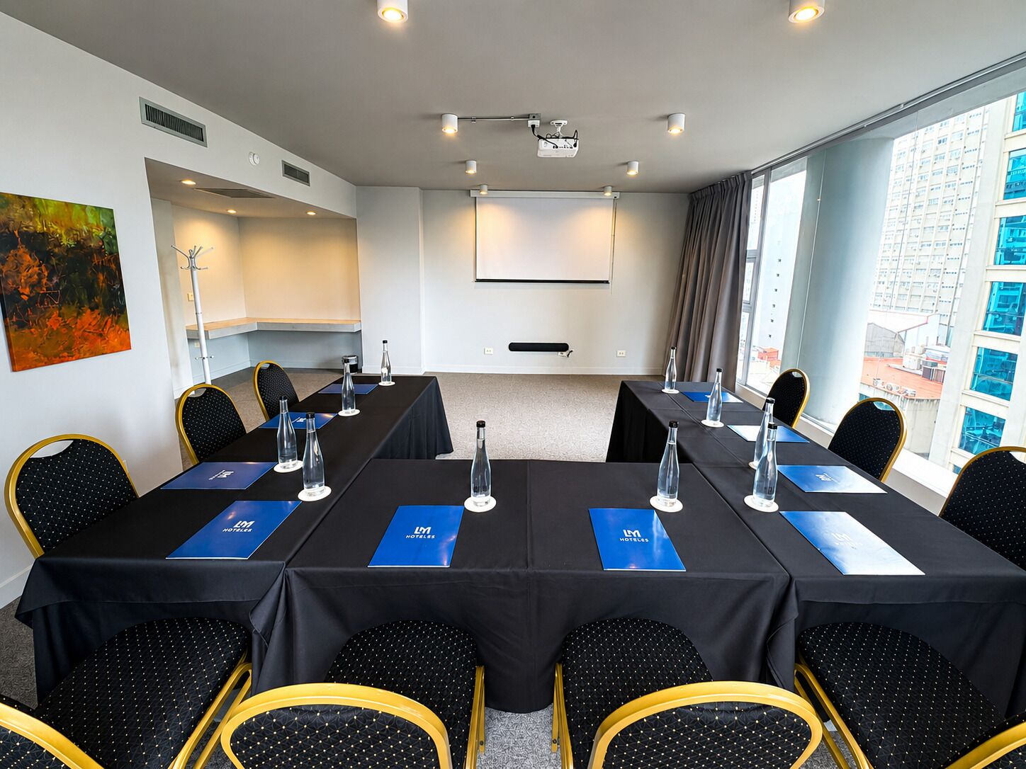 A conference room with a long table, chairs, and a projector screen.