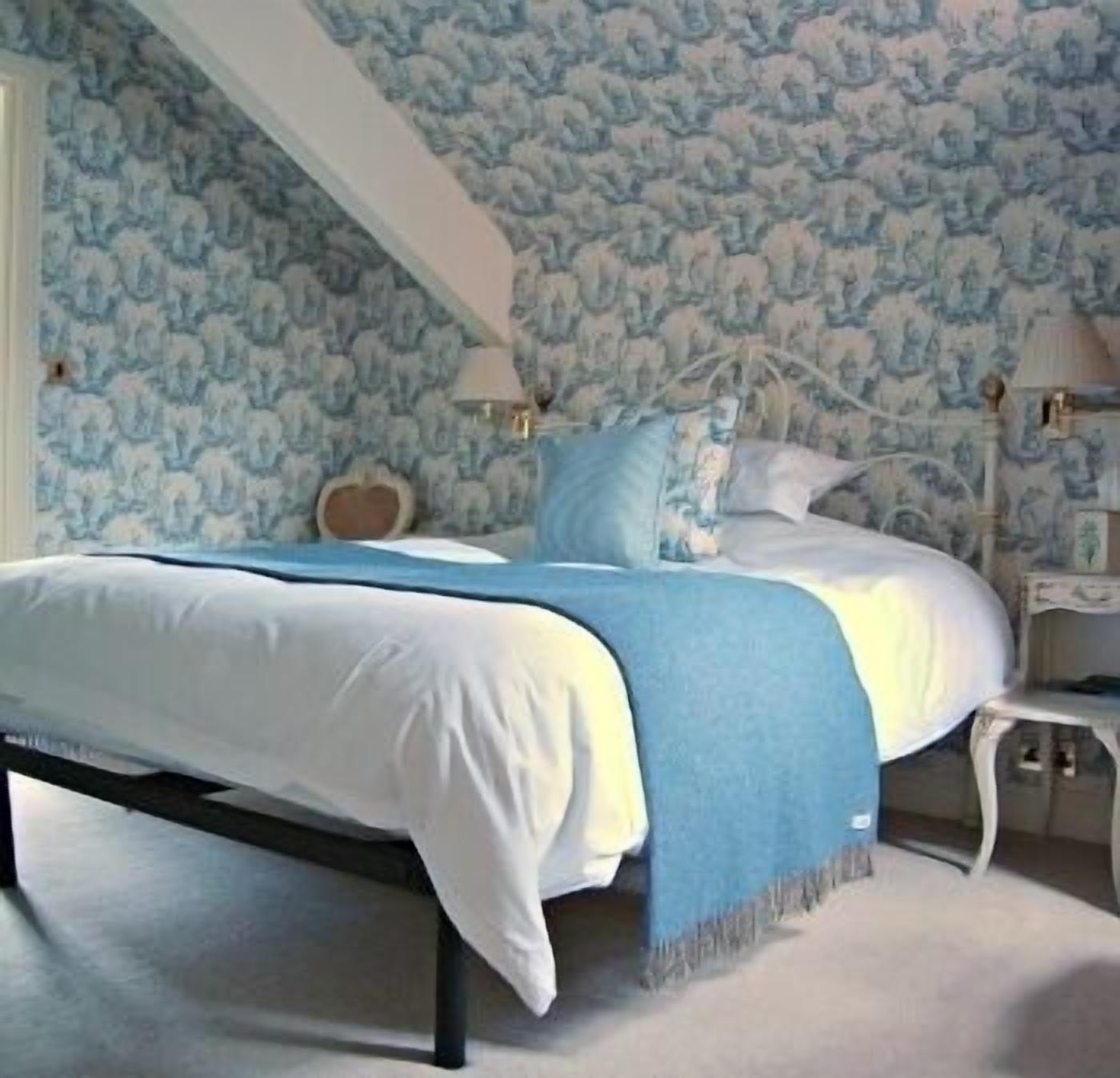 Un dormitorio con cama, mesita de noche y pared decorada con un diseño azul y blanco.