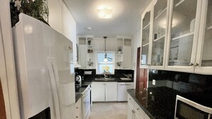 A kitchen with white cabinets, a black countertop, and a refrigerator. - 4BR, 4BA House Beach, Entertainment, Nightlife (Hollywood)