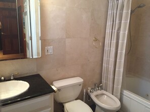 A bathroom with a sink, toilet, bidet, and shower curtain.