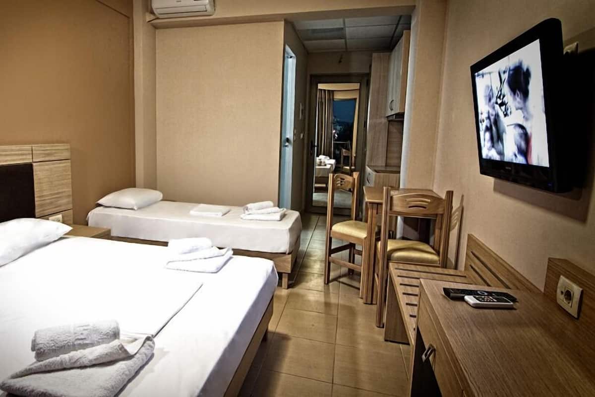 A hotel room with two beds, a TV, a desk with a phone, and a chair.