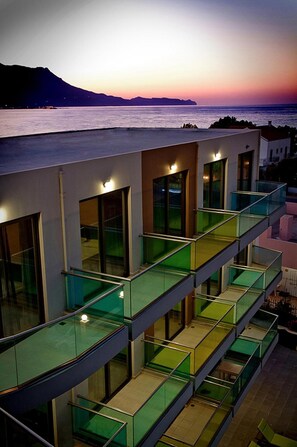 A modern building with multiple balconies overlooking a body of water at sunset. - Crystal Bay (Kissamos)