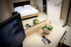 Ein Hotelzimmer mit einem Bett, einem Fernseher, einem Schreibtisch mit einer Pflanzenbowl und einer Fernbedienung.