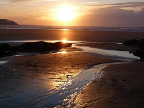 A beach with a sunset, waves, and rocks. - High Ways House (Ilfracombe)