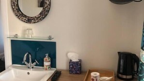 A bathroom with a sink, mirror, and a flat-screen TV mounted on the wall. - High Ways House (Ilfracombe)