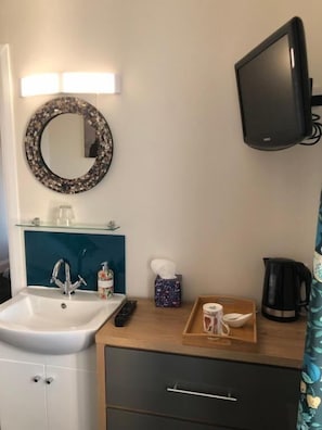 A bathroom with a sink, mirror, and a flat-screen TV mounted on the wall. - High Ways House (Ilfracombe)