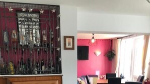 A dining area with a wooden table and chairs, a red accent wall, and a decorative metal gate. - High Ways House (Ilfracombe)