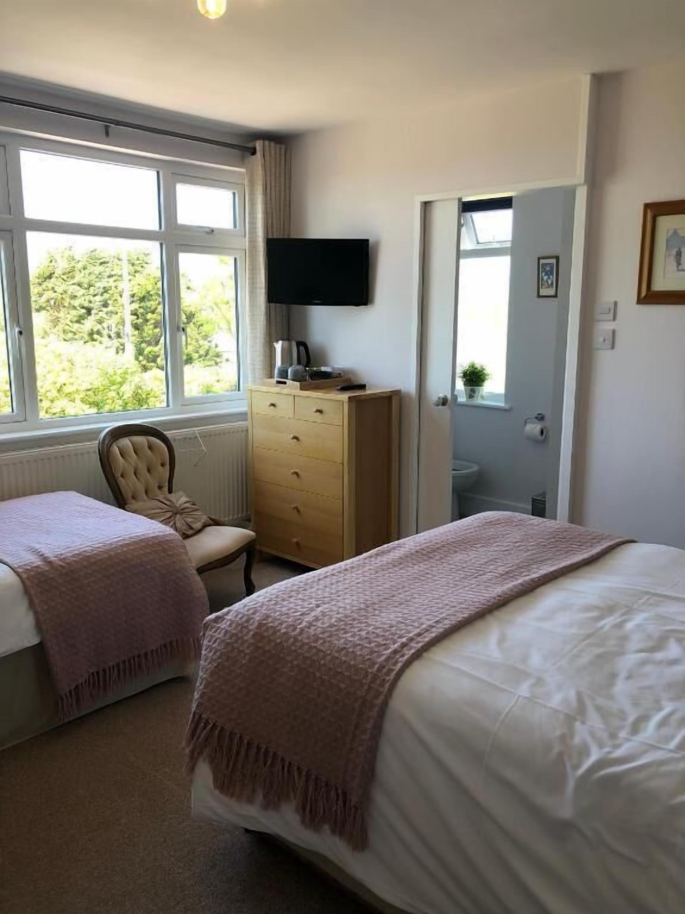 Une chambre à coucher avec un lit, une chaise, une commode, un téléviseur et une fenêtre.