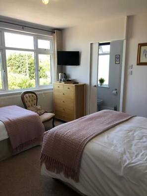 A bedroom with a bed, a chair, a dresser, a television, and a window. - High Ways House (Ilfracombe)