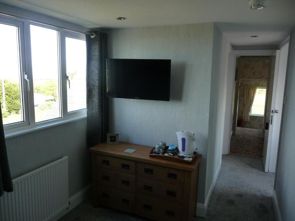 Ein Zimmer mit einem an der Wand befestigten Fernseher, einem Holzschrank und einer Heizung.