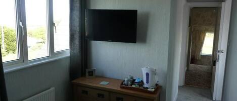 Ein Zimmer mit einem an der Wand befestigten Fernseher, einem Holzschrank und einer Heizung.