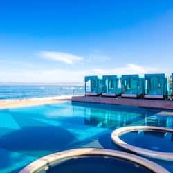 Relax by the serene pool, surrounded by a tranquil beach setting and comfortable lounge chairs.