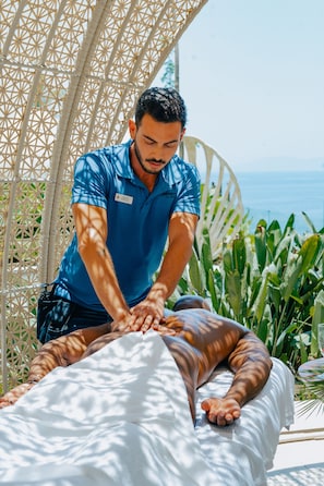 A person receiving a massage in a room with a view of the sea.
