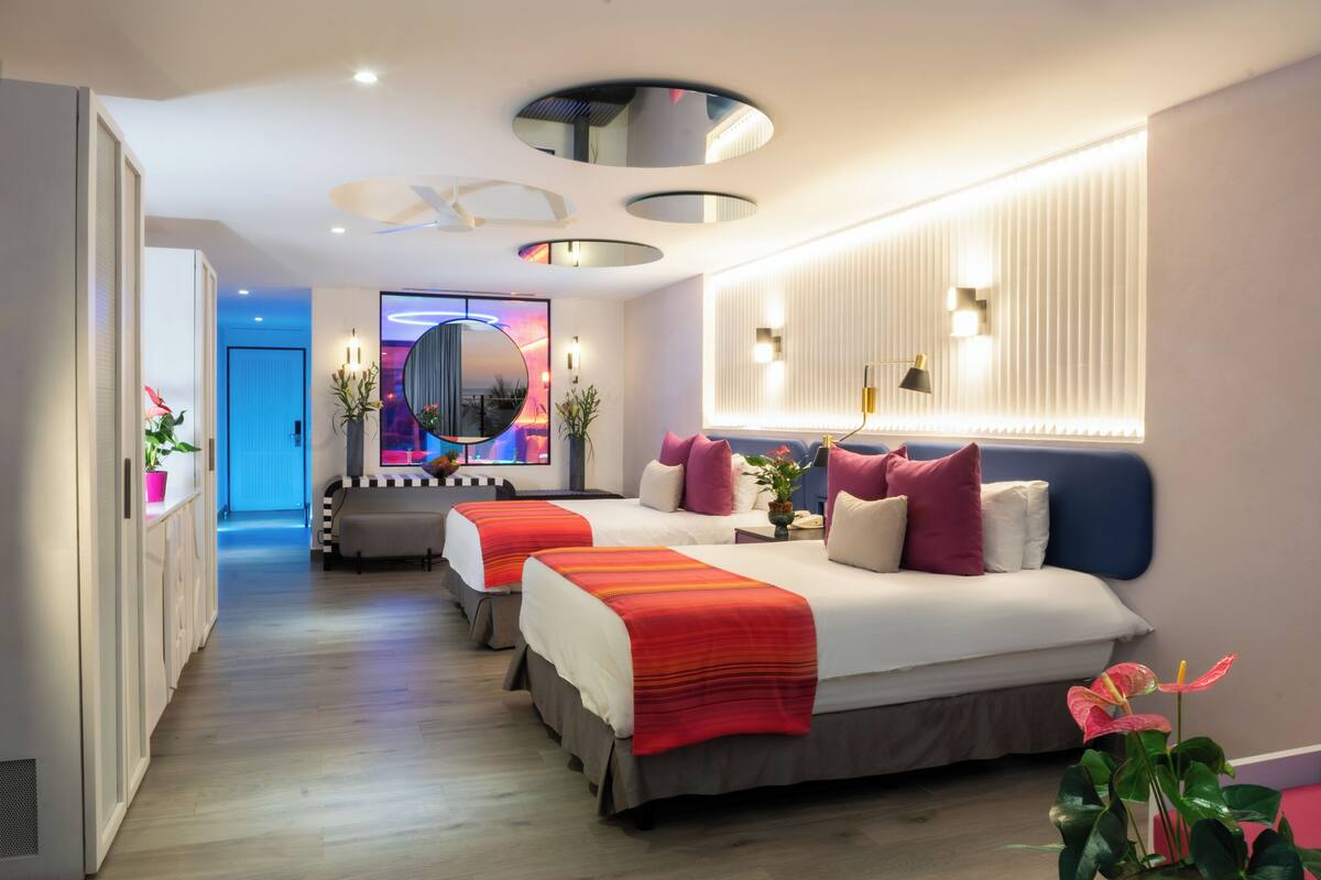 Una habitación de hotel moderna con una cama grande, un escritorio y un espejo.